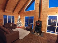 a living room filled with furniture and a christmas tree in front of a windowed wall