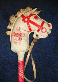 a white horse head on top of a red and white pole with a brown ribbon around it