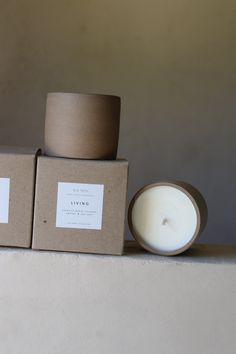 two candles sitting next to each other in front of a box with labels on it