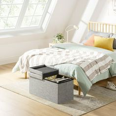 a bedroom with a bed, nightstand and storage box on the floor in front of it