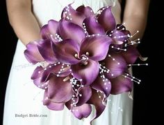 a bridal bouquet with purple flowers and pearls