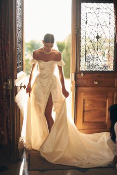 a woman in a white dress is standing by a door