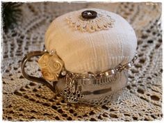 a silver tea pot sitting on top of a doily covered table next to a pine tree