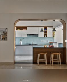 an open kitchen with two stools in front of the counter and cabinets on the wall