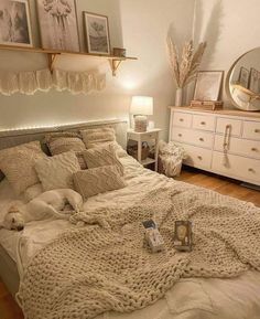 a dog laying on a bed in a room with white furniture and pictures above it