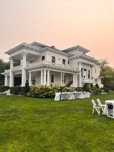 a large white house sitting on top of a lush green field next to a lawn