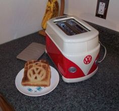 a toaster sitting on top of a counter next to a plate with a slice of bread