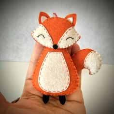 a hand holding a small stuffed animal that looks like a fox