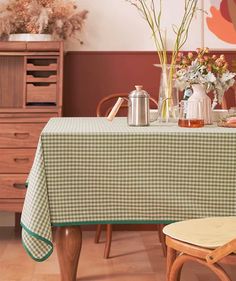 a green and white checkered table cloth on a dining room table with flowers in vases