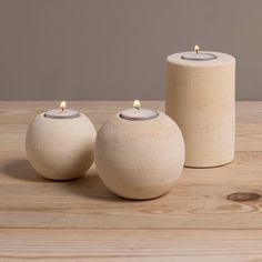 two white candles sitting on top of a wooden table