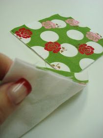 a hand holding a piece of fabric next to a napkin with flower designs on it