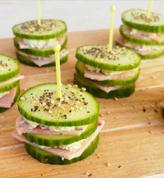 cucumber sandwiches with toothpicks are arranged on a cutting board, ready to be eaten