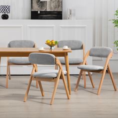 a dining room table with four chairs and a bowl of fruit on the table next to it