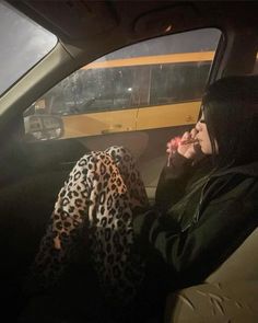 a woman sitting in the passenger seat of a car with her hand on her mouth