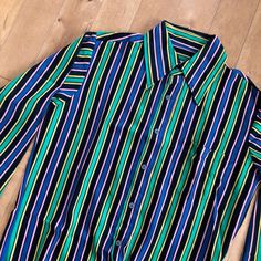 "This piece is a vintage men's striped long sleeve button up shirt from the 1980s. This collared shirt has a knit style multicolour fabric in great colours.  -Made in Taiwan, Bad Berma -100% Nylon  -One small stain on the left shoulder Tag Size: Medium *refer to measurements for true fit* Pit to Pit: 21\" Length: 26\" Please also assess the photos and measurements carefully using your own personal judgement as we do not accept returns. Keep in mind that this is a piece of vintage clothing that may hold a residual scent from its past. While we wash all of the clothing we sell (except for certain items which are steam cleaned) we cannot guarantee that we have been able to remove all of the stubborn scents. Buyers should be prepared for the possibility of having to wash the items again once t Retro Striped Button-up Shirt, Retro Long Sleeve Shirt With Vertical Stripes, 1980s Mens Fashion, 80s Mens, Paisley Shirt, Long Sleeve Button Up Shirt, Mens Stripes, Knit Style, Purple Shirt