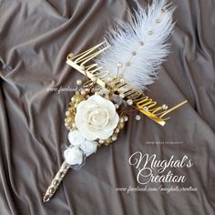 a bridal hair comb with white flowers and feathers on a gray sheeted surface