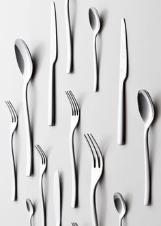 forks and spoons are arranged on a white surface