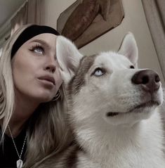 a woman is sitting next to a husky dog