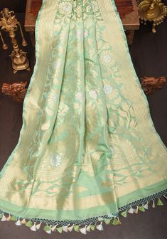 This Alfi Sona Rupa Banarasi Saree in Pista Green is crafted from luxuriously fine Katan Silk, renowned for its luminous quality. Detailed with two-tone zari, the body, borders, and pallu feature a magnificient floral Jaal pattern, reflecting upon the fine weaving traditions of Banaras. SILK MARK CERTIFIED This saree is ready to wear with fall and pico done. Handmade silk tassels adorn the pallu and add more grace to it. An unstitched blouse fabric is included. *Note: There may be minor variations in the shade, the texture of the product. Hues/textures show differently due to variations in screen settings and other factors, *Note: This is a handwoven saree and there may be slight inconsistencies such as in it's weaving. These are characteristic of handmade products and attest to their orig Silk Banarasi Saree, Pista Green, Silk Tassels, Katan Silk, Banarasi Saree, Banarasi Sarees, Blouse Fabric, Handmade Products, Saree Wedding