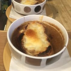 two bowls filled with food sitting on top of a wooden table next to each other