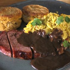 a plate with meat, rice and biscuits on it