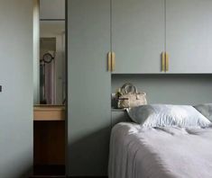 a white bed sitting in a bedroom next to a wall mounted cabinet and clock above it