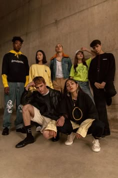 a group of young people standing next to each other in front of a cement wall