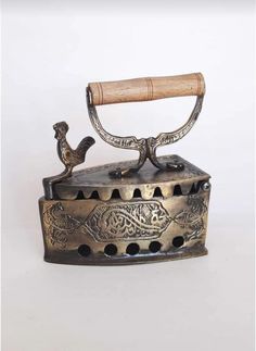 an old fashioned metal box with a bird on the top and a wooden stick sticking out of it