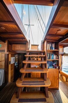 the inside of a boat with wooden stairs and bookshelves