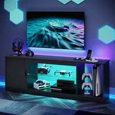 an entertainment center with a large television on it's wall and various gaming accessories in front of it