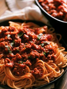 a plate of spaghetti with meat sauce and parmesan cheese on the side, ready to be eaten