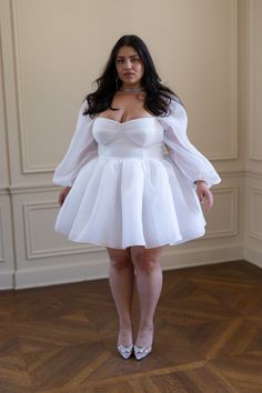 a woman in a white dress posing for the camera with her hands on her hips