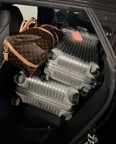 three pieces of luggage sitting in the back of a car