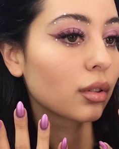 a woman with pink nail polish holding her hands up to her face and looking at the camera