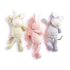 three stuffed animals are laying next to each other on a white surface and one is wearing a striped sweater