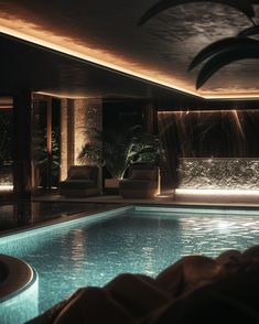 an indoor swimming pool with lights on the ceiling and water running down the wall behind it