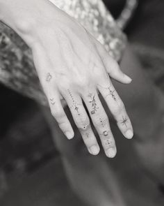 a woman's hand with stars and moon tattoos on her left thumb, while the other hand is in black and white