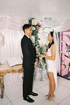 a man and woman standing next to each other in front of a table with flowers on it