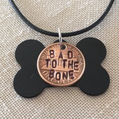 a dog tag with the words bad to the bone on it is attached to a leather cord