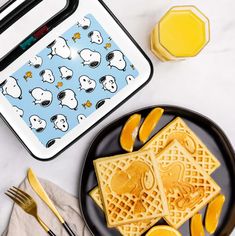 a plate with waffles and orange slices on it next to a lunch box