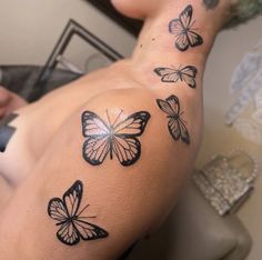 a woman with tattoos on her back and butterflies tattooed on her arm, sitting in a chair