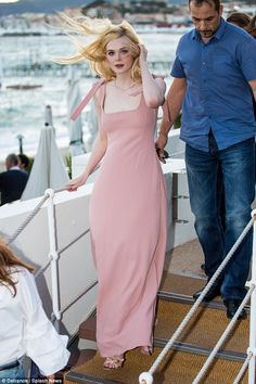 a woman in a pink dress is walking down the stairs with her hair blowing in the wind