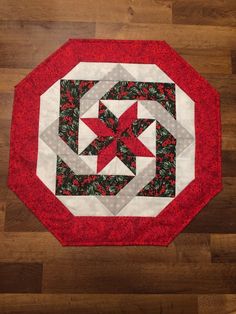 a red and white quilted table topper on a wooden floor