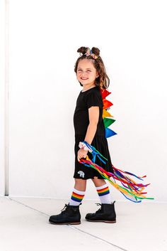 "Rainbow dinosaur spike girls twirly dress will be a favorite with your little fashion toddler girl. Kids dinosaur dress makes a sweet birthday gift or St Paddy's outfit for the little one on your list. Handcrafted spikes are sewn on to create a dino dressup costume they'll love. Our twirly skirt dinosaur dress is fun for pretend play and equally matched for hanging out. Dinosaur spike dress has short sleeves and is made with a black pleated Rabbit Skins dress with felt spikes stitched down the Multicolor Ruffle Twirl Dress For Playdate, Multicolor Ruffled Twirl Dress For Playdate, Playful Rainbow Dress With Ruffles, Playful Short Sleeve Twirl Dress For Playdate, Multicolor Playful Twirl Dress For Play, Playful Multicolor Twirl Dress For Play, Cute Rainbow Dresses With Ruffles, Cute Rainbow Ruffled Dresses, Playful Short Sleeve Twirl Dress