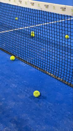 several tennis balls are on the blue court