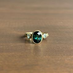 A bewitching teal tourmaline is elegantly positioned between a pair of beryls in this dazzling ring. 14k green gold Tourmaline 7mm x 9mm (1/4" x 3/8")Beryls 3mm (1/8") in diameterSapphires 1mm in diameter Oval Tourmaline Emerald Ring With Bezel Setting, Jewelry Making Classes, Newport Ri, Aqua Marine, Three Stone Rings, Three Stone, Green Gold, Bracelet Gift, Ring Necklace