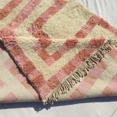 a pink and white blanket laying on top of a bed