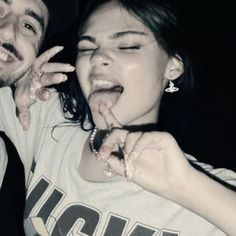 two people posing for the camera with their hands on their mouths and one person sticking out his tongue