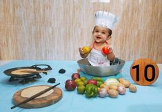 a baby in a chef's hat is sitting in a pan with vegetables on the table