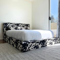 a bed sitting in the middle of a room with a cow print headboard and foot board